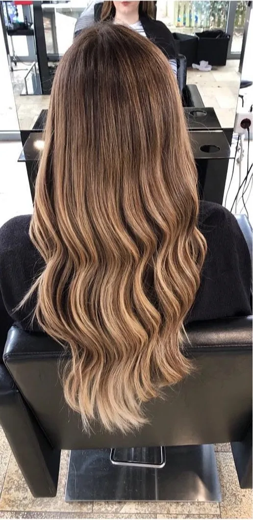 Nachher: dieselbe Kundin mit Balayage in Blond und weichen Wellen, Rückansicht im Salon Haar Exakt
